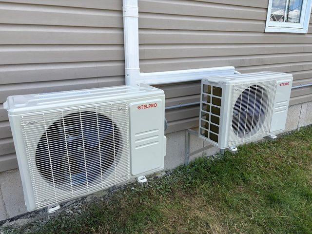 Two Stelpro mini split outdoor units with line covers installed on a home